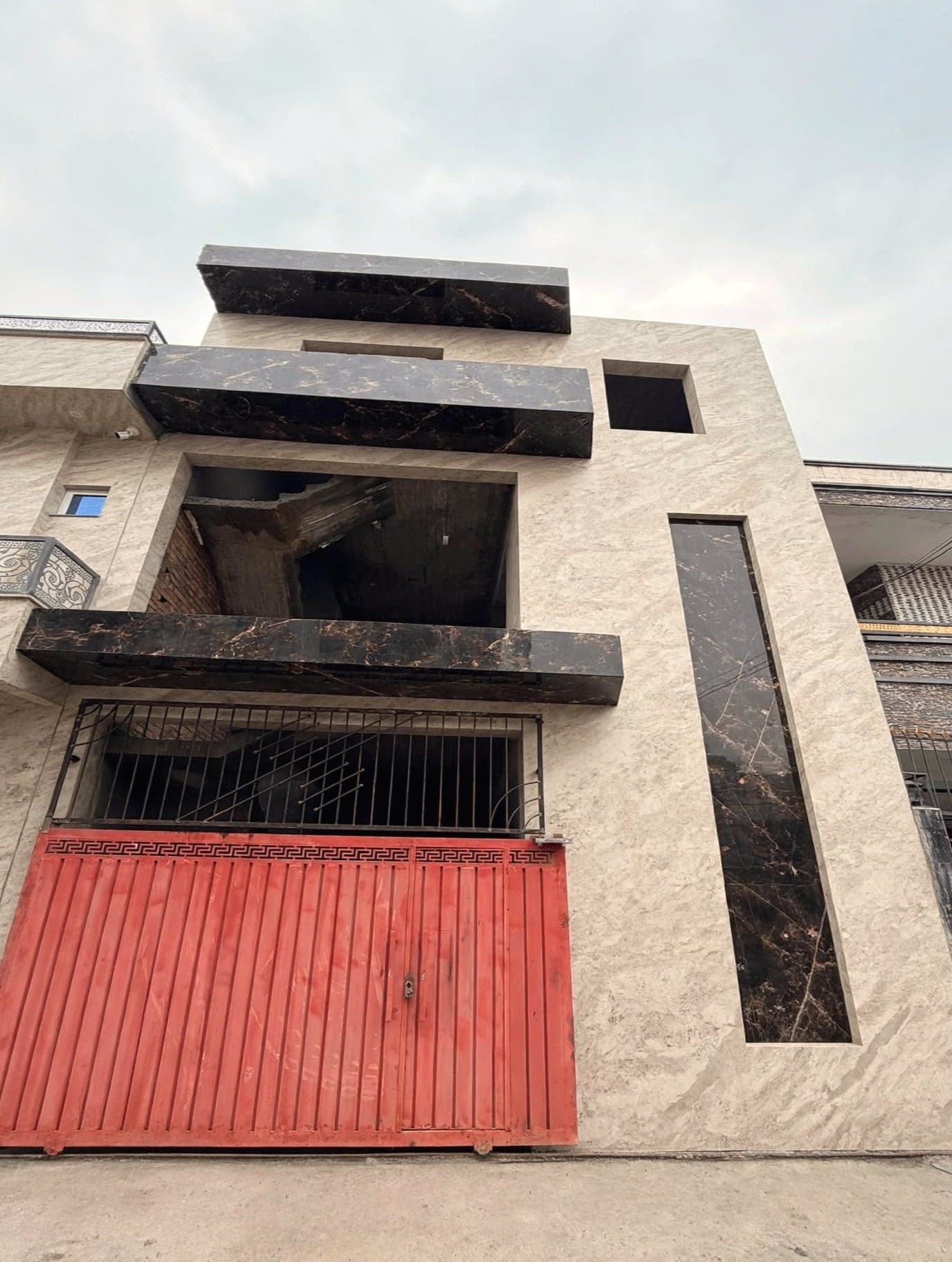 The same house front clad in travertine and dark marble