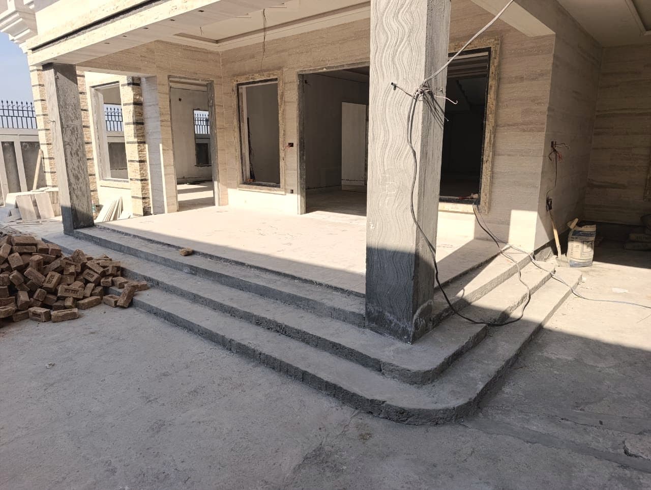 A porch in bare grey concrete, before any stone is laid